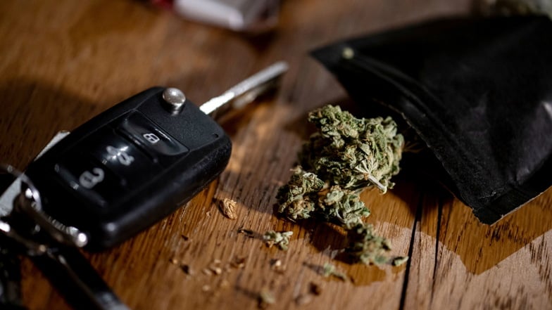 Cannabisblüten liegen auf einem Tisch neben einem Autoschlüssel: Für Autofahrerinnen und Autofahrer gelten jetzt neue Bestimmungen und Bußgelder für Cannabis am Steuer.