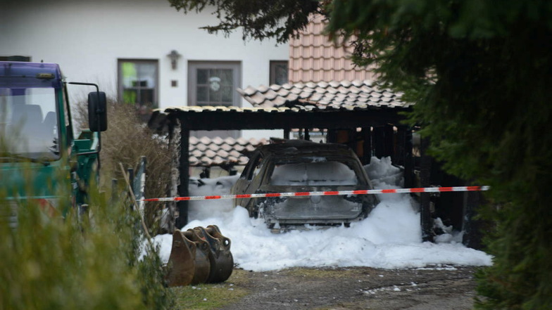 Löschschaum umhüllt den VW Golf, der unter einem Carport stehend in Brand geraten war.