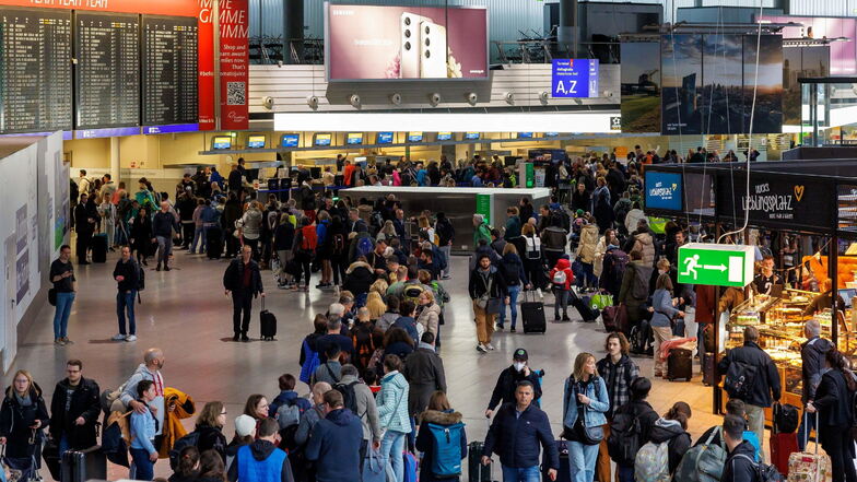 Passagiere stehen im Terminal 1 in einer Schlange. Nach dem Warnstreik der Gewerkschaft Verdi müssen Passagiere am Frankfurter Flughafen an diesem Samstag noch mit Verzögerungen und einzelnen Flugstreichungen rechnen.