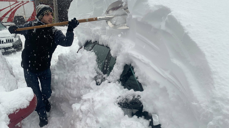 Patrick Werth befreit im österreichischen Sillian mit einer Schaufel sein Auto von den Schneemassen.
