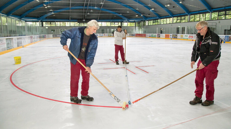 Mitarbeiter der Stadtwerke Niesky ziehen die Linien auf der frischen Eisfläche für die bevorstehende Eislaufsaison. Das war vor vier Wochen. Seit dieser ist das Eisstadion geschlossen.