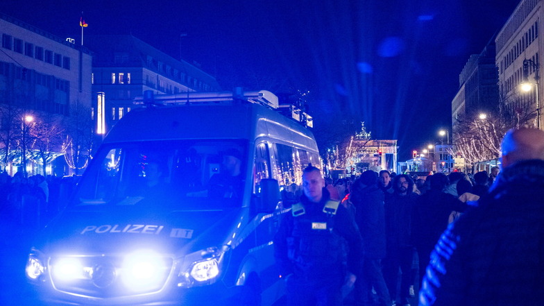 Ein Polizeiauto fährt vor dem Brandenburger Tor mit Blaulicht durch die Menschenmenge.