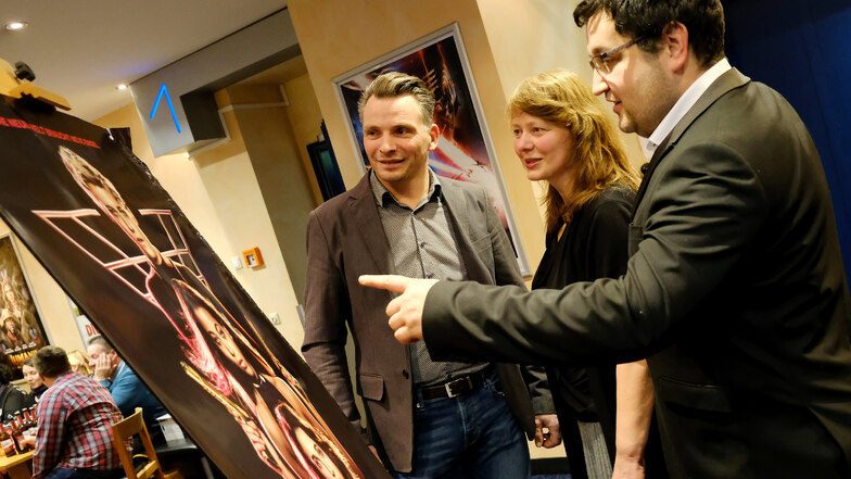 Kinochef Alexander Malt (rechts) zeigt der Moritzburger Schlossleiterin Dominique Fliegler und ihrem Kollegen Daniel Maaz ein Filmplakat.