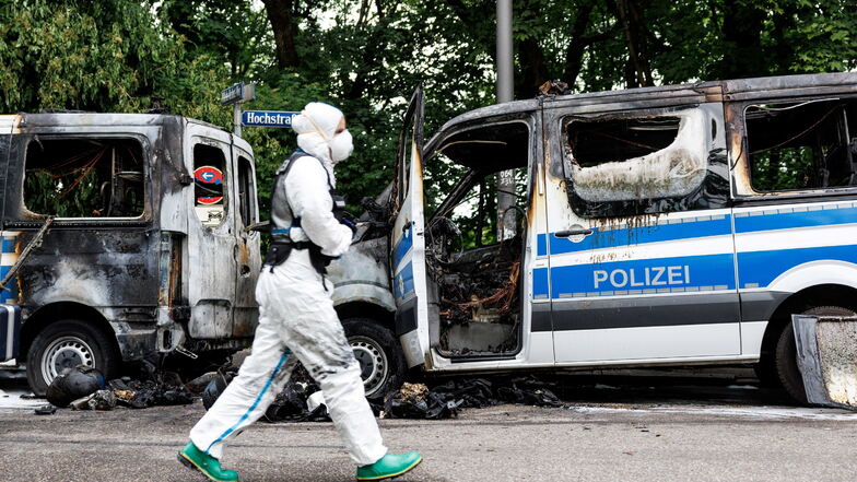 Ein Ermittler der Spurensicherung geht Polizeiautos vorbei, die in der Nacht in München gebrannt hatten. Die Mannschaftsbusse der Bundesbereitschaftspolizei stehen vor einem Hotel, in dem Polizisten für den G7-Gipfel untergebracht sind.