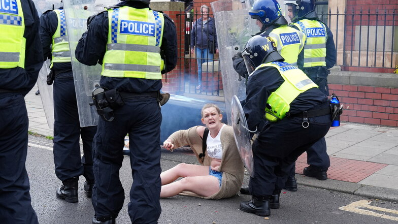 Ein Polizeibeamter hilft einer gestürzten Frau während einer Anti-Einwanderungsdemonstration in Middlesbrough.