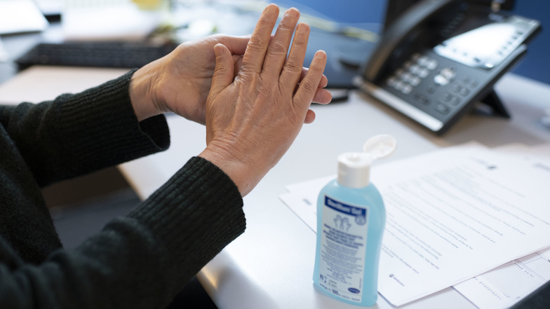 Eine Person reibt sich am Arbeitsplatz die Hände mit einem Desinfektionsmittel ein. Das Coronavirus hat auch Auswirkungen auf die Arbeitswelt.