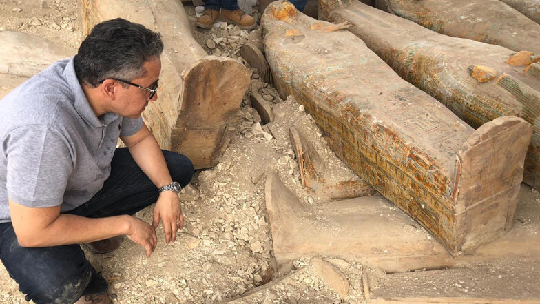 Khaled al-Anany, Ägyptens Minister für Altertümer, untersucht einen der neu entdeckten alten Holzsärge mit Inschriften und Gemälden. 