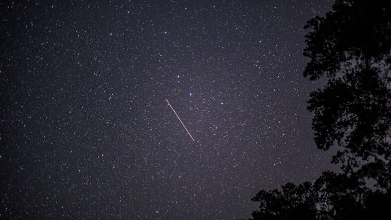 Ein vorbeifliegender Satellit ist am nächtlichen Sternenhimmel als Lichtspur zu sehen.