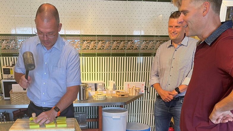 Landrat Ralf Hänsel stempelt Seifen unter den Blicken von Weinböhlas Bürgermeister Siegfried Zenker (hinten) und Dirk Schneider (rechts).