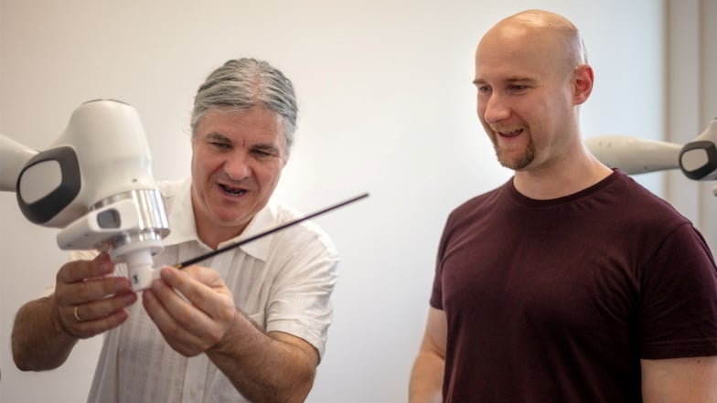 Markus Rindt und Frank Peters (r.) vom Exzellenzclusters CeTI bei der gemeinsamen Arbeit mit dem Dirigierroboter.