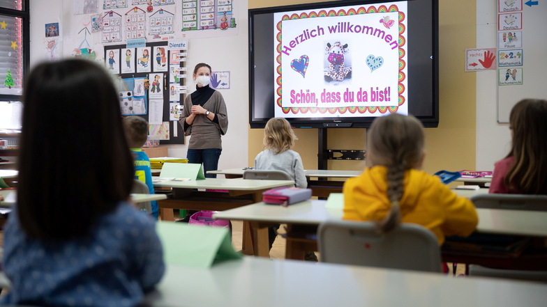 Eine Lehrerin mit FFP2-Maske unterrichtet in einer ersten Klasse an einer Grundschule mit Wechselunterricht. Sachsen will nach den Ferien auch Grundschüler testen.