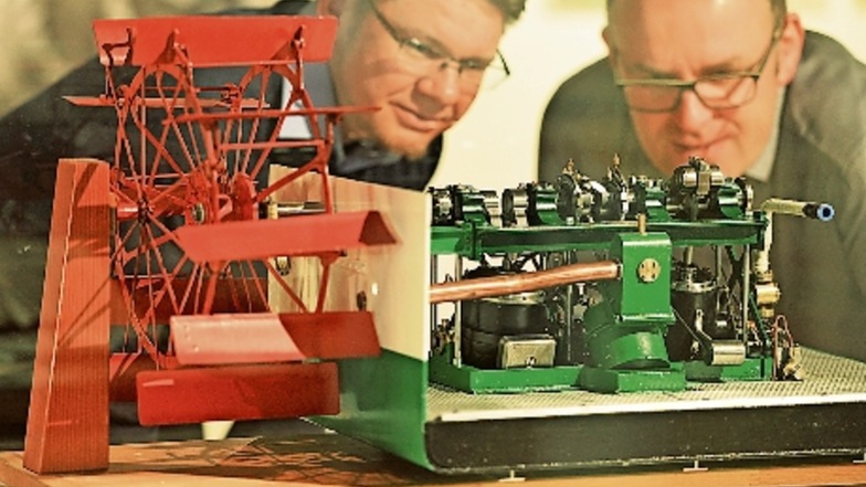 Falk Hering (l.) und Michael Kaiser schauen sich in der neuen Schifffahrt-Ausstellung im Pirnaer Stadtmuseum das Modell einer Dampfmaschine an, die ein Schaufelrad antreibt.