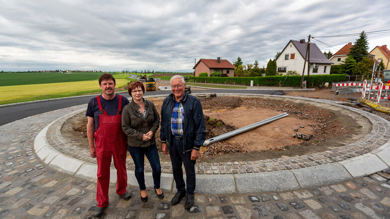Frank und Heike Köhler und Hermann Clausnitzer (v.l.) stehen am Kreisverkehr, der im Auftrag des Landkreises am Ortseingang Kleinopitz derzeit errichtet wird.