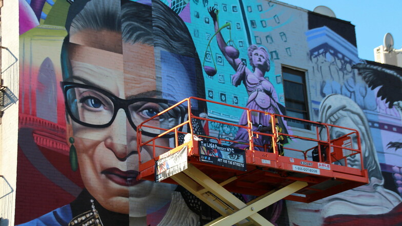 Künstler legen letzte Hand an ein buntes Gemälde an einer Hauswand im East Village in Manhattan an.