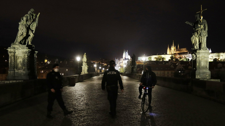 Noch gelten strenge Regeln in Tschechien: Polizisten kontrollieren auf der ansonsten menschenleeren Karlsbrücke in Prag einen Radfahrer.