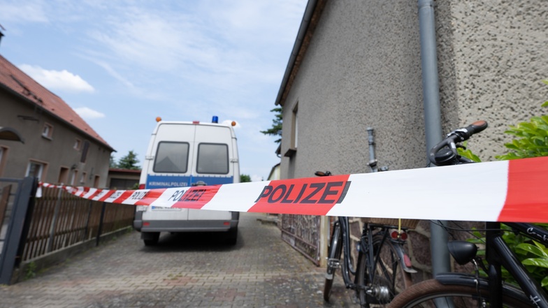 Ein Absperrband hängt vor einem Wohnhaus. Nach dem Fund einer Leiche in einem Haus im Landkreis Oberspreewald-Lausitz ermittelt die Mordkommission in Cottbus zu einem Gewaltverbrechen.