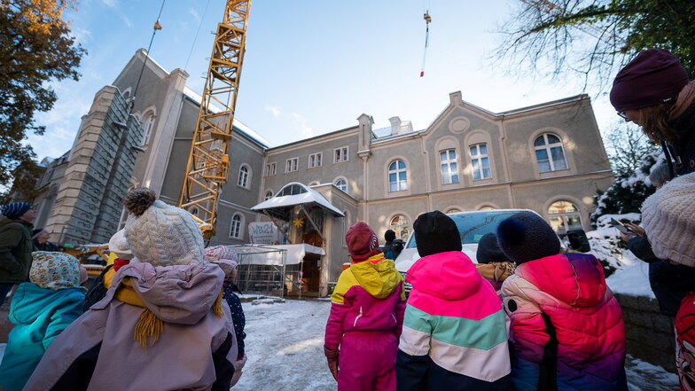 Die Kindergartenkinder der Kita „Samenkorn“ staunen über den Kran auf der Baustelle am Jugendhaus Wartburg in Görlitz. Am Kranhaken schwebt ein roter Beutel für sie heran.