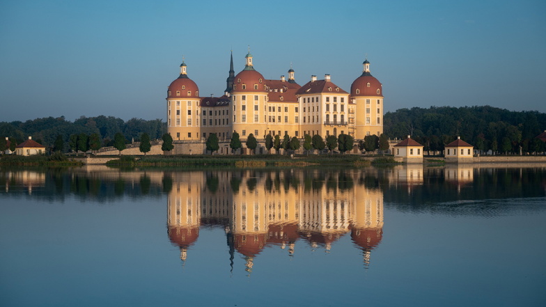 Schloss Moritzburg, einstiges Jagdschloss der Wettiner, wird am Morgen vom Sonnenlicht angestrahlt.