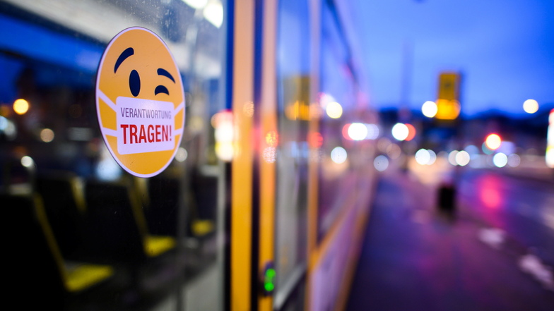 Mit maskierten Smileys und der Aufschrift "Verantwortung tragen" wird in an Bussen und Bahnen in Dresden auf die Maskenpflicht verwiesen. Doch nicht alle Fahrgäste halten sich daran.