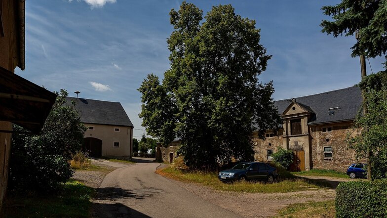 Auf dem Hof des ehemaligen Ritterguts in Colmnitz spendet der große Baum Schatten, auch für parkende Autos.