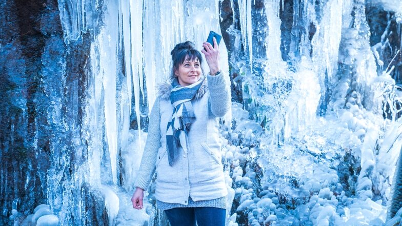 Ist das nicht eine bezaubernde Kulisse? Mechthild Steiner macht vor den riesigen Eiszapfen an Felsen nahe Glashütte mit Ihrem Handy ein Selfie. Foto: Ronald Bonss