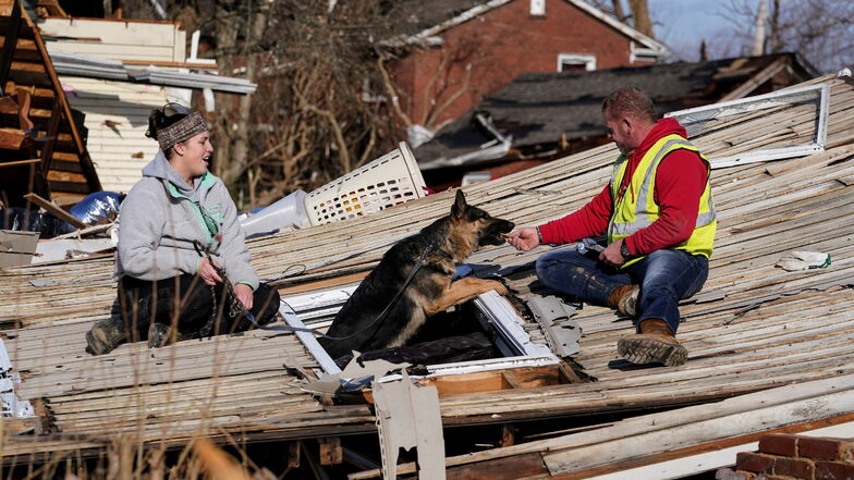 Mayfield: Chris Buchanan (r) lockt den Hund Cheyenne mit Hilfe von Niki Thompson (l) aus einem vom Tornado beschädigten Haus. Tornados haben in den USA eine Schneise der Verwüstung durch mehrere Bundesstaaten geschlagen und zahlreichen Menschen das Leben 