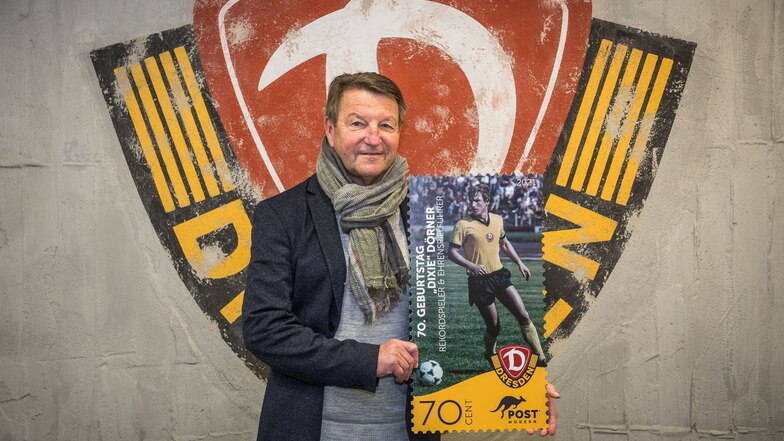 Dynamos Ehrenspielführer Hans-Jürgen „Dixie“ Dörner präsentiert die Sonderbriefmarke, mit der er zum 68. Vereinsgeburtstag gewürdigt wird.