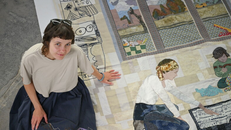 „Diplomarbeit“: Die ukrainische Künstlerin Dariia Kuzmych sitzt in der Dresdner Robotron-Kantine auf dem Quilt, den sie gemeinsam mit ihrer Mutter Svitlana Seleznova gestaltet hat.