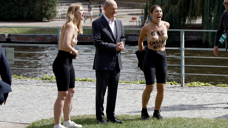 Aktivistinnen protestieren mit nackter Brust neben Scholz für ein Gasembargo