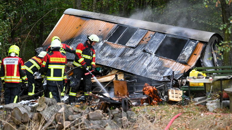 Feuerwehrleute löschen den ausgebrannten Bauwagen bei der Jäckelbaude in Ebersdorf.