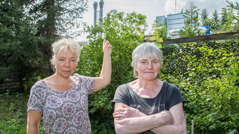 Annette Eichler (links) steht mit Nachbarin Gisela Przybyl in ihrem Garten an der Muskauer Straße. Im Hintergrund die Abluftanlage des Möbelwerkes.  Foto: André Schulze