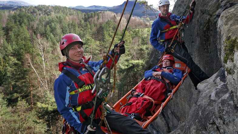 Lisa Hoffmann (vorn) und Stephan Roth von der Bergwacht Dresden beim Abseilen mit einer Trage. Lisa Dornwell von der Bergwacht Sebnitz mimt die Verletzte in der Trage.