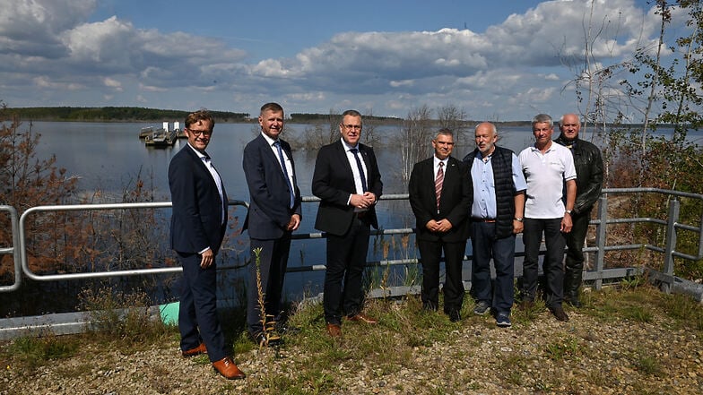 Brandenburgs Infrastrukturminister Rainer Genilke (3.v.l.) schaute sich am Montag am Sedlitzer See an, wie es mit dem Schwimmenden Steg im Hintergrund weiter gehen soll.