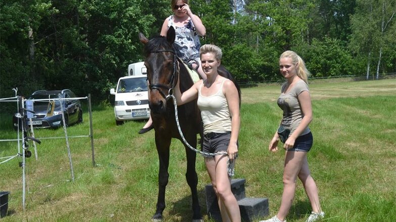 Theresa Schneider und Jessica Schneider vom Pferdehof Jerchwitz helfen Isabell während des Kinderreitens beim Aufitzen auf Ritti.
