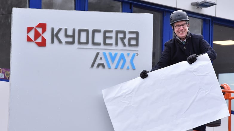 Werkleiter Thorsten Bick enthüllt die Stele am Eingang mit dem Schriftzug Kyocera AVX.