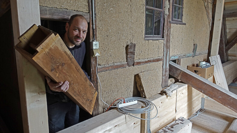 Orgelbauer Felix Tibussek schaut aus der Tür der Balgkammer. Mächtige Leimbinder fangen den Einbau unter dem Dach ab.