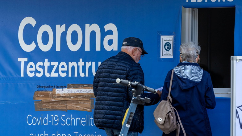 Passanten stehen vor einem Corona-Testzentrum. In Deutschland steigen die Corona-Kennzahlen wieder deutlich an.