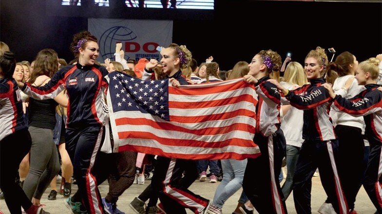 Noch bevor der Stepptanz-Abend startet, feiern die Tänzer nach der Präsentation aller Mannschaften auf der Bühne ihren Sport. Besonders laut singen, hüpfen und steppen die Amerikaner mit ihrer Nationalflagge.