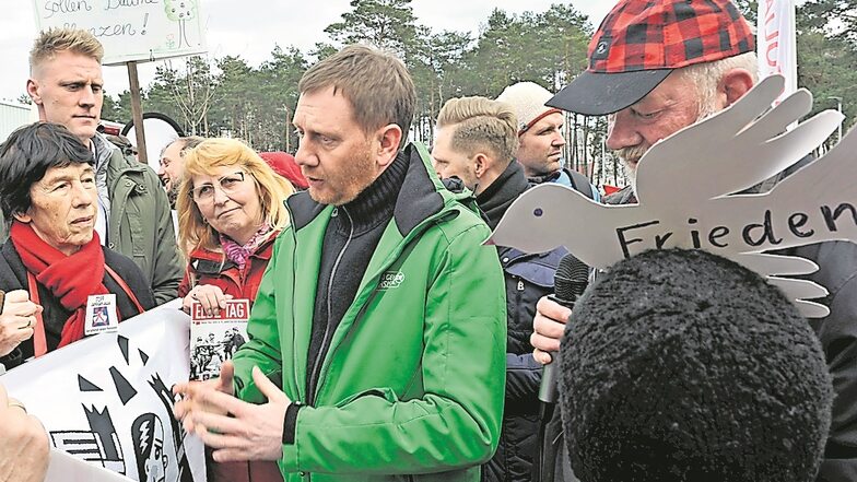 Sachsens Ministerpräsident Michael Kretschmer (Mi.) stellte sich in Weißwasser auch Fragen von Demonstranten wie der Berliner Friedensaktivistin Barbara Fuchs 