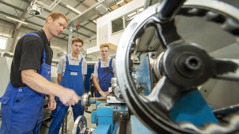 Neue Maschinenhalle im Bildungszentrum Pirna: Ausbilder Thomas Werner (l.) erklärt den Industriemechaniker-Azubis Tom Behrendt und Felix Kazimiers (r.) eine Drehmaschine.