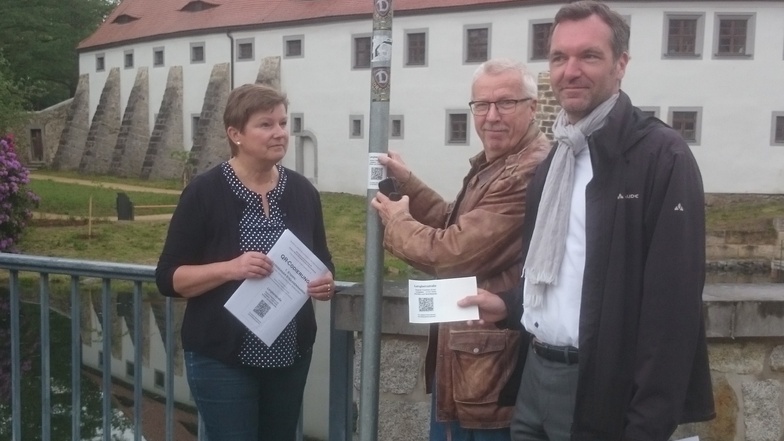 Radebergs Ordnungsamtsleiterin Elke Müller, Klaus Schönfuß von der AG Stadtgeschichte und Wirtschaftsreferent Marco Wagner haben an der Langbeinstraße einen QR-Code angebracht.