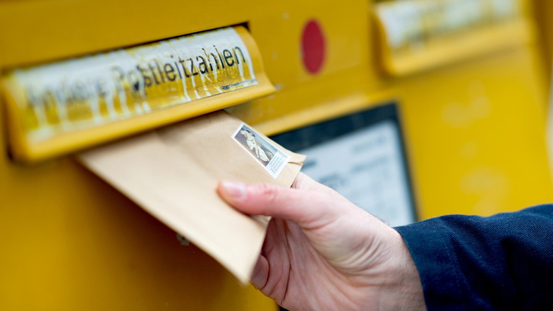 Ein Briefumschlag wird in einen Briefkasten geworfen.