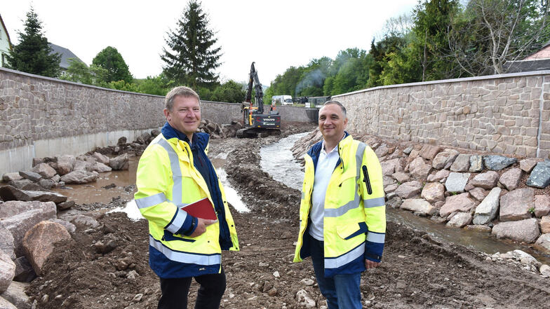 Thomas Rothe (li.) und Stefan Leonhardt stehen hier zwischen den hohen Hochwasserschutzmauern, die jetzt die Rote Weißeritz in Ulberndorf im Zaum halten sollen.