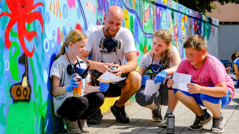 Wie geht es mit dem Wandbild weiter? Alina, Till Mixsa, Nadine und Erik (v.l.n.r.) besprechen die nächsten Schritte beim Sprühen der Graffitis mit den Abenteuern des Schulfisches.