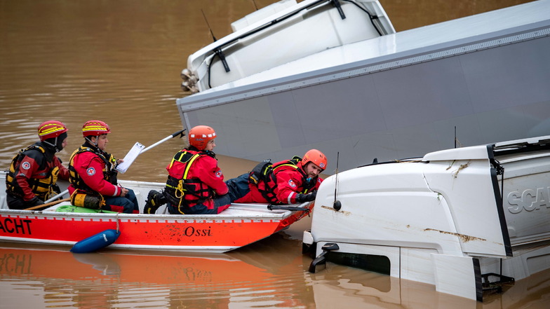 Helfer der Wasserwacht untersuchen von einem Boot aus Lastwagen. Auch Helfen aus Sachsen haben sich auf den Weg in die Katastrophenregion gemacht.