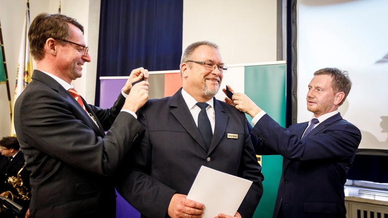 Hier bekommt der aktuelle Polizeipräsident 2019 seine neuen Schulterstücke: Der Sächsische Innenminister Roland Wöller (links) und Ministerpräsident Michael Kretschmer (rechts) bringen sie Manfred Weißbach an.