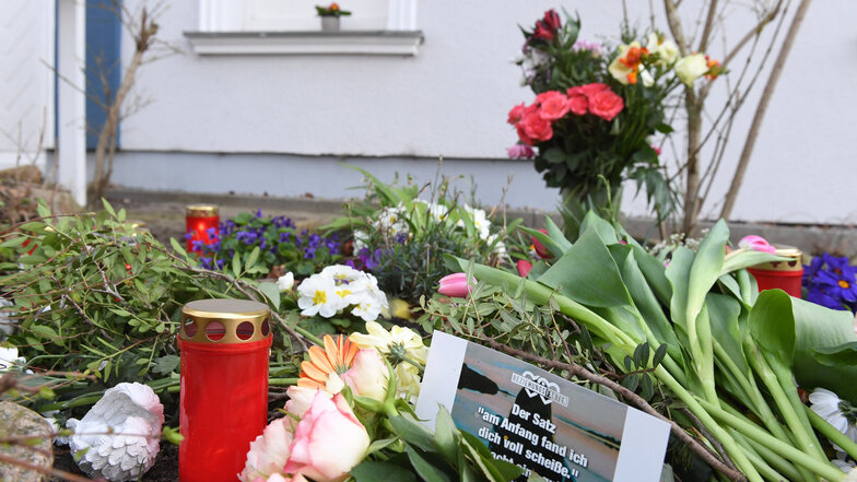 Kerzen und Blumen stehen vor dem Eingang des Hauses in Zinnowitz, in dem am 19. März 2019 eine 18-jährige Frau tot aufgefunden wurde.