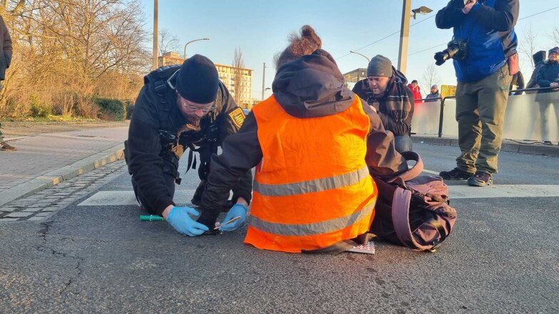Mit Spritzen, in denen sich Öl befindet, versuchen Polizisten, die Hände der Klima-Demonstranten von der Straße am Lennéplatz zu lösen.