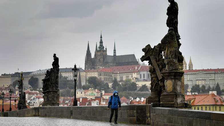 Ein Mann geht bei Regen über die leere Karlsbrücke in Prag. Auch am Wochenende stiegen die Infiziertenzahlen in Tschechien.