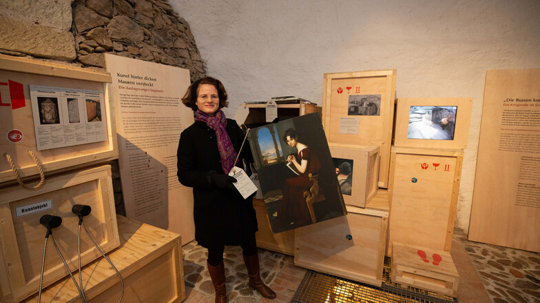 Kustodin Birgit Finger steht in der Ausstellung "Bombensicher" in der Folterkammer mit einem Druck des Gemäldes "Junge Dame mit Zeichengerät" von Carl Christian Vogel von Vogelstein aus dem Jahre 1816.